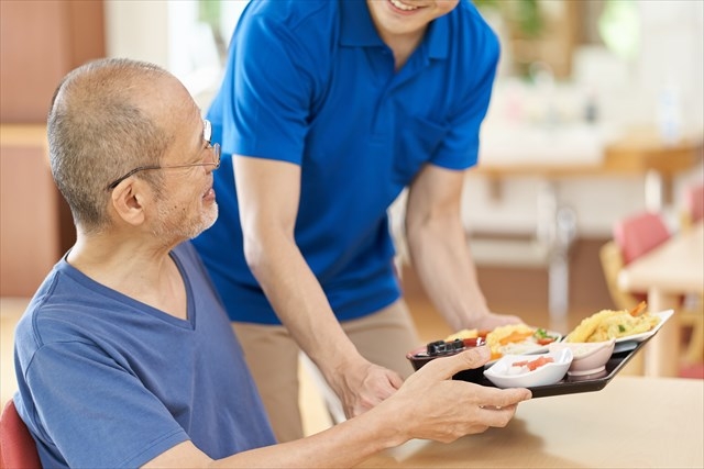 A nurse aide gently assisting a senior client with a meal